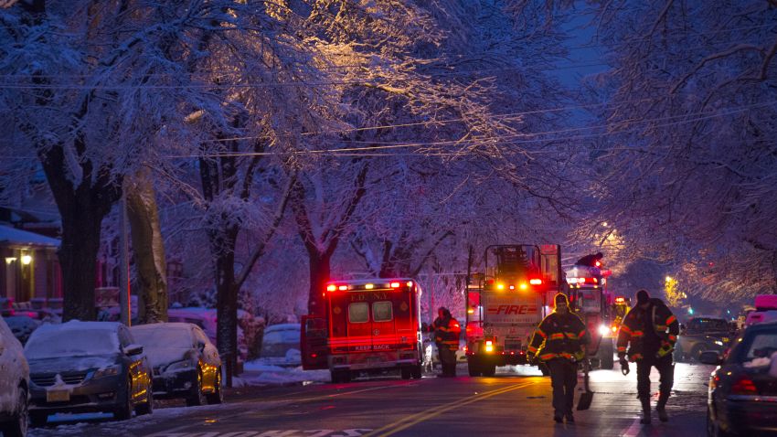 Firefighters walk near the scene of a fire, center left, in which seven children died in the Brooklyn borough of New York Saturday, March 21, 2015. (AP Photo/Craig Ruttle)