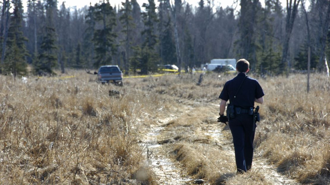 A police officer walks to a temporary camp where officials are working to identify remains of what Kenai police think are a family missing since May.