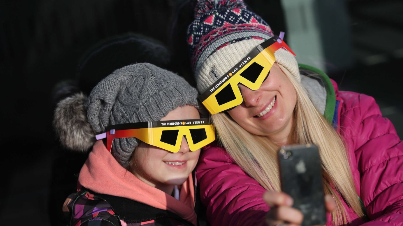 A mother and daughter wear special glasses to help them view a solar eclipse Friday, March 20, in Swansea, Wales.