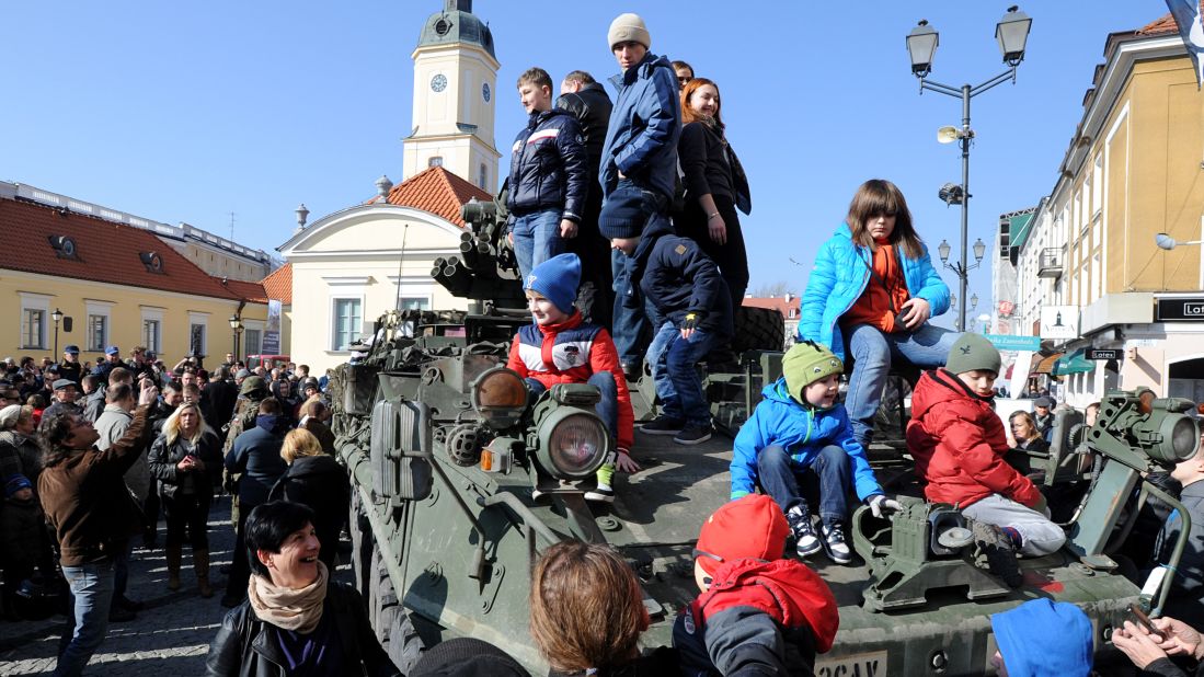 People surround a group of U.S. Army armored vehicles from the 3rd Squadron, 2nd Cavalry Regiment, on March 24 in Bialystok. The convoy started in Estonia and passed through Latvia and Lithuania before entering Poland on its way to a base in Germany.