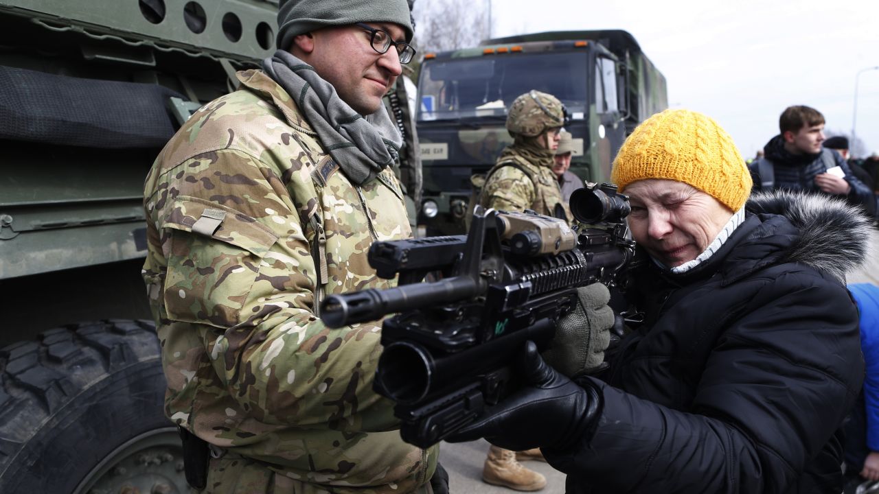 A member of the 2nd Cavalry Regiment shows a gun to a woman on Monday, March 23, in Salociai, north of the Lithuanian capital of Vilnius.