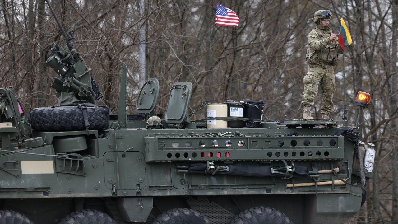 A U.S. soldier raises the Lithuanian flag on a Stryker vehicle on March 23 in Salociai.