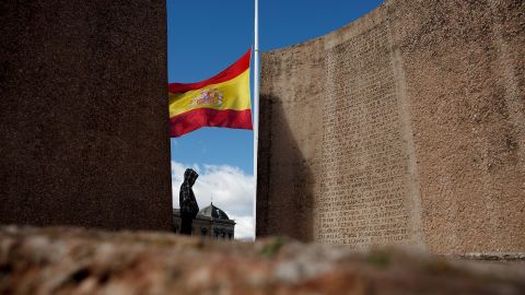 A person in Madrid stands near a Spanish flag flying at half-staff on March 25.