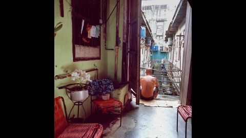 A man sits in the doorway of a communal living house.