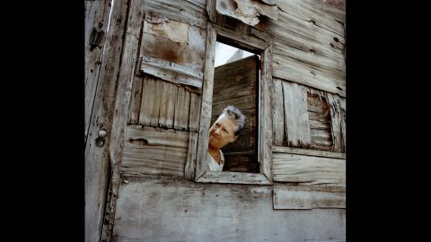 A woman looks out from a solar in Havana.