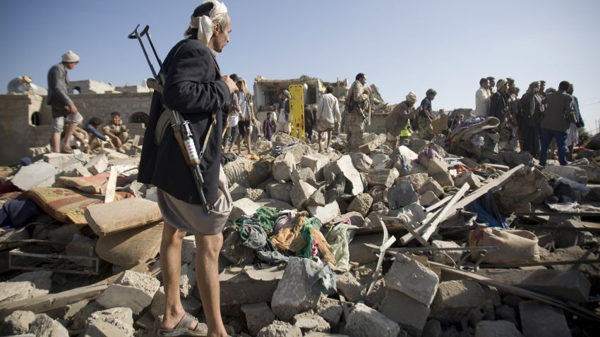 A Houthi Shiite fighter stand guard as people search for survivors under the rubble of houses destroyed by Saudi airstrikes near Sanaa Airport, Yemen, Thursday, March 26, 2015. Saudi Arabia launched airstrikes Thursday targeting military installations in Yemen held by Shiite rebels who were taking over a key port city in the country's south and had driven the embattled president to flee by sea, security officials said. (AP Photo/Hani Mohammed)
