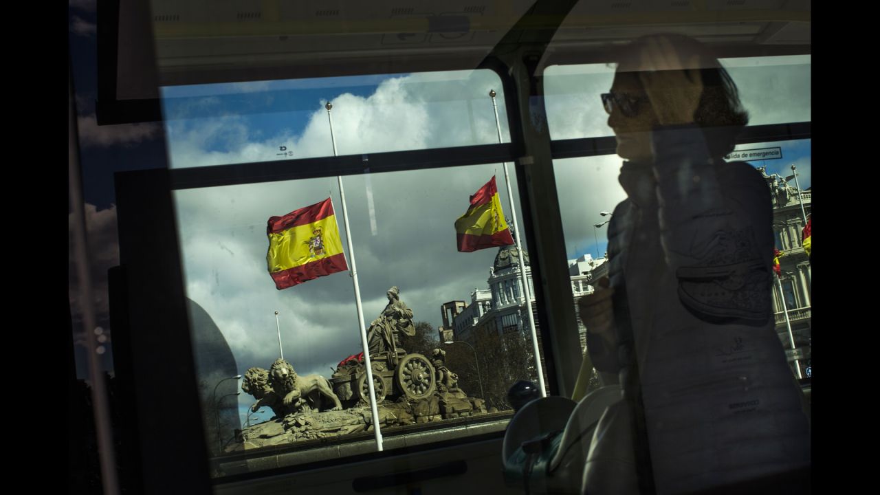 A woman uses public transit in Madrid as flags fly at half-staff on March 25.