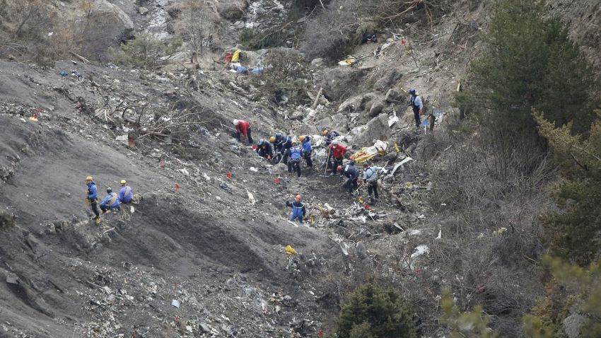 Rescue workers work on debris of the Germanwings jet at the crash site near Seyne-les-Alpes, France, Thursday, March 26, 2015. The co-pilot of the Germanwings jet barricaded himself in the cockpit and "intentionally" rammed the plane full speed into the French Alps, ignoring the captain's frantic pounding on the cockpit door and the screams of terror from passengers, a prosecutor said Thursday. In a split second, he killed all 150 people aboard the plane. (AP Photo/Laurent Cipriani)