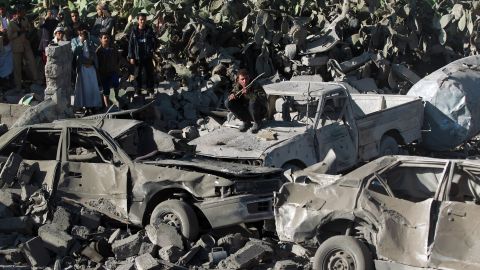 People gathered around burned vehicles after Saudi-led airstrikes against the Houthis near Sanaa Airport on March 26.