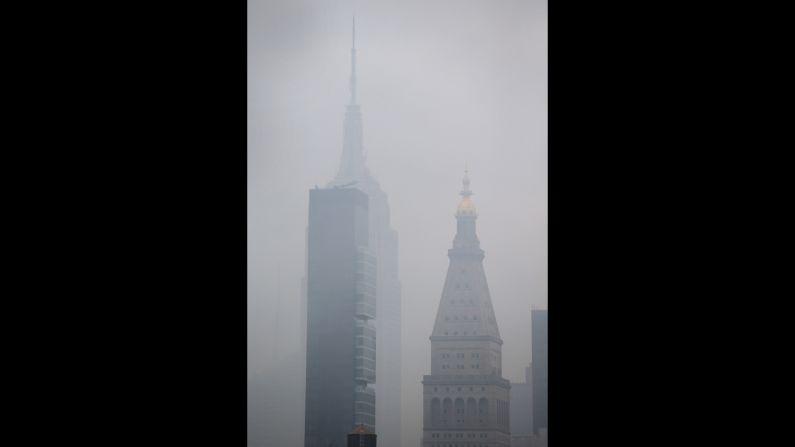 The Empire State Building can be seen through the smoke caused by the fire. 