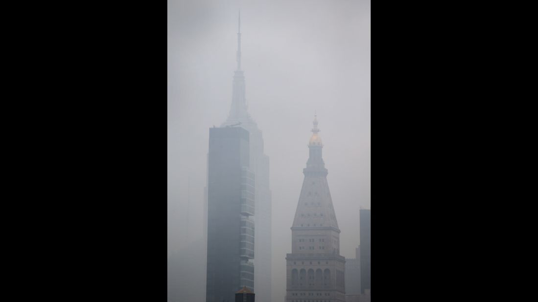 The Empire State Building can be seen through the smoke caused by the fire. 