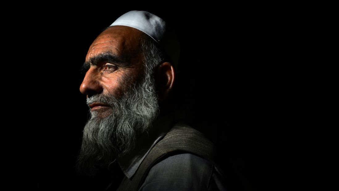 An Afghan man spends a moment alone in a military planning room before serving tea to soldiers on June 11, 2014. 
