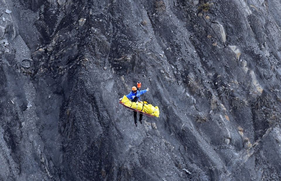 A helicopter lifts a rescue worker from the crash site on March 26.