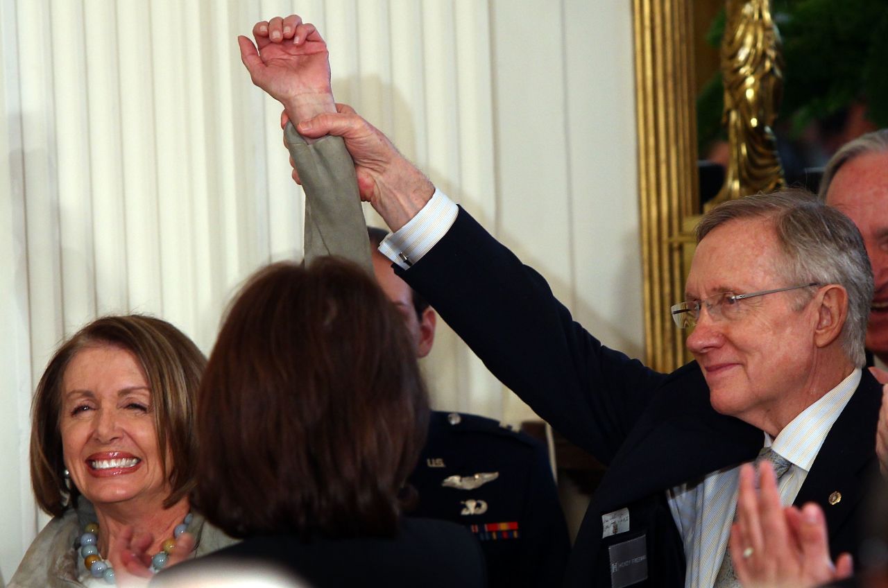 Pelosi and Reid throw their hands up as Obama introduces them during the signing ceremony for the Affordable Health Care for America Act in the East Room of the White House on March 23, 2010.