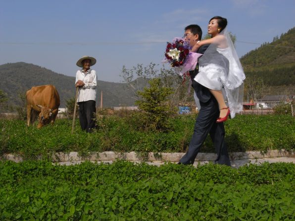 A groom carries his bride through a field in Baishan, Jilin province in 2007 as an old man looks on. Wang's work often reveals the clashes between tradition and modernity in China.