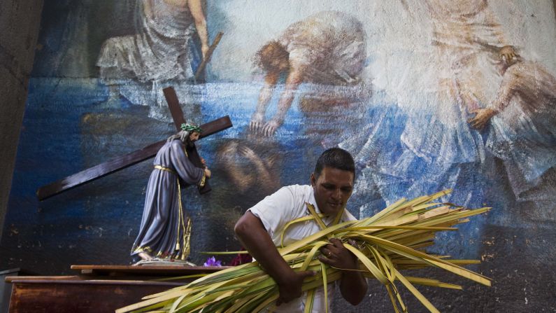 A church volunteer carries an armful of palm fronds to be given to parishioners at the Metropolitan Cathedral in Managua on March 29.