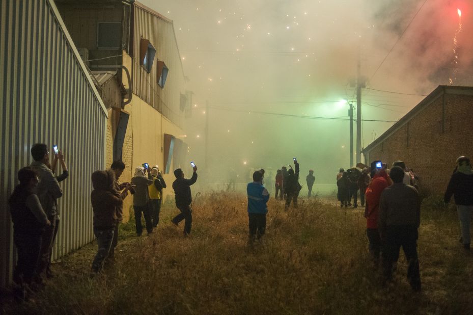 Not everyone wants to stand in the middle of the action. These attendees -- wreathed in sulfur fumes -- watch the fireworks from the safety of a vacant lot. 