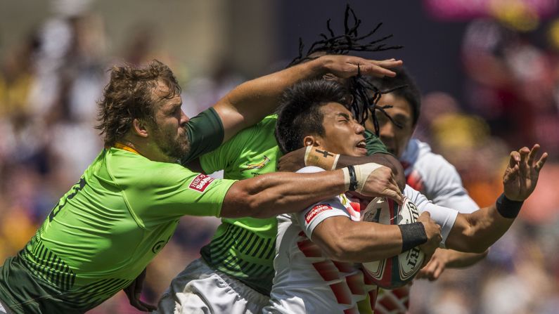 Japanese rugby player Rakuhei Yamashita is tackled by South African players during a Hong Kong Sevens match Saturday, March 28, in Hong Kong.