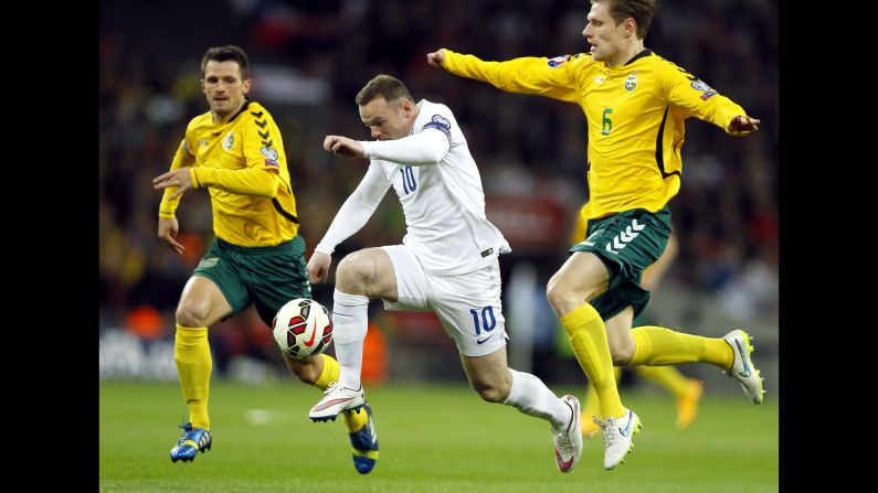 England's Wayne Rooney dribbles past Lithuanian defenders during a Euro 2016 qualifying match Friday, March 27, in London. Rooney scored the opening goal in England's 4-0 victory.