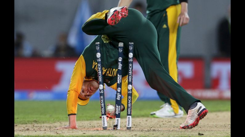 South African captain AB de Villiers tumbles over the stumps during a failed run-out attempt on New Zealand's Corey Anderson during a Cricket World Cup semifinal played Tuesday, March 24, in Auckland, New Zealand. New Zealand won by four wickets.