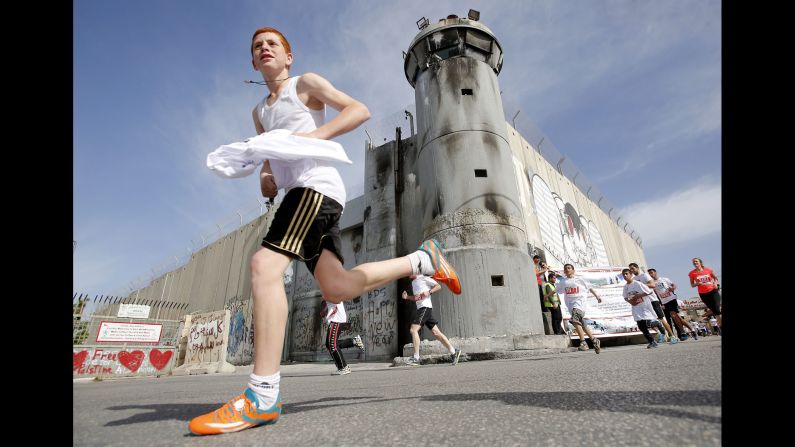 A runner passes Israel's separation barrier in Bethlehem, West Bank, while participating in the <a href="index.php?page=&url=http%3A%2F%2Fwww.cnn.com%2F2015%2F03%2F28%2Fmiddleeast%2Fpalestine-marathon%2F" target="_blank">Palestine Marathon</a> on Friday, March 27.