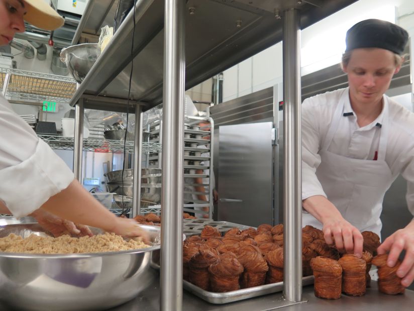 Mr. Holmes Bakehouse pastry chef and co-owner Ry Stephen (right) wrangles cruffins fresh from the oven. They'll be dusted with sugar in a moment then sold to customers lined up outside.