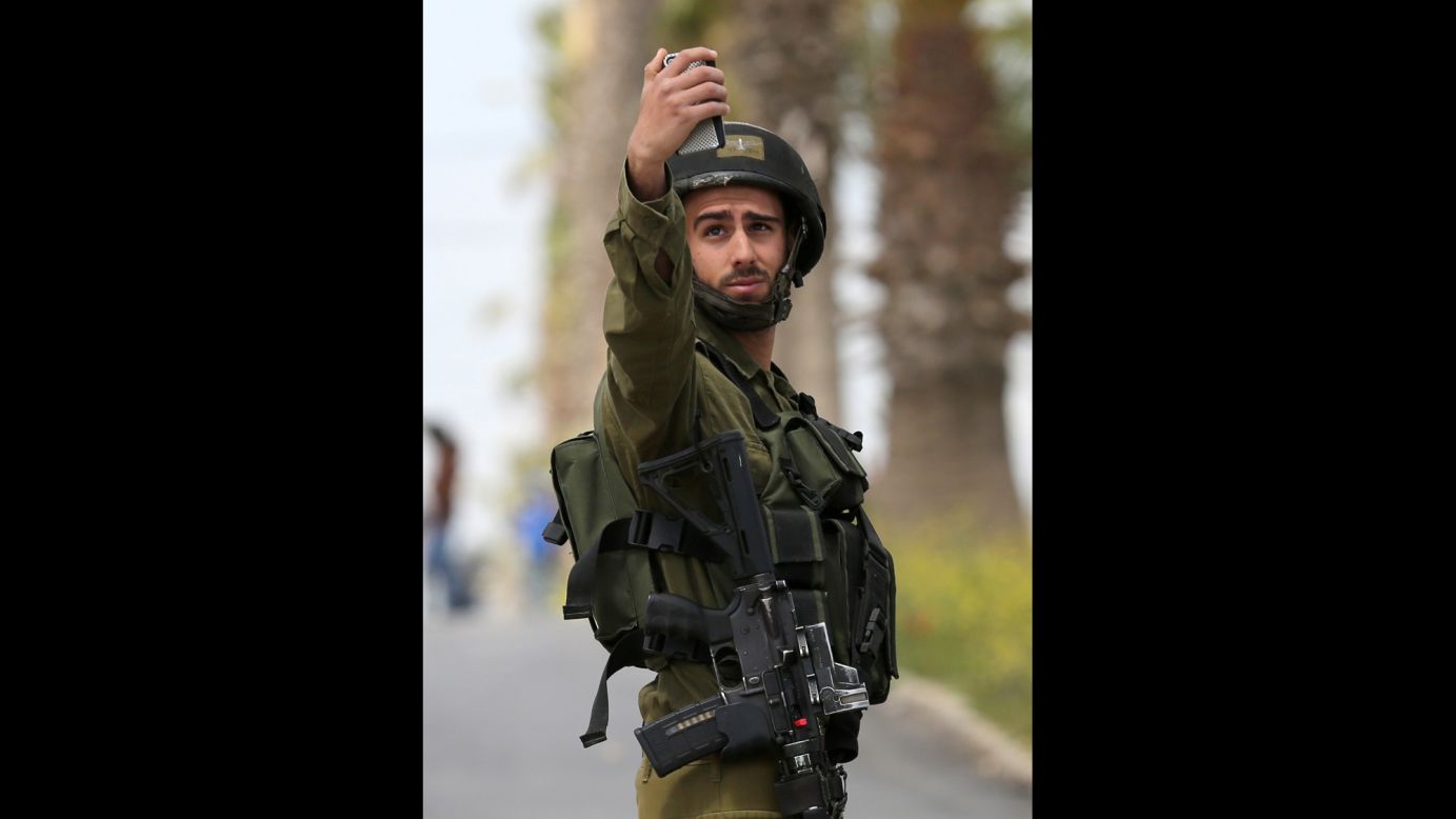 An Israeli soldier takes a selfie following a protest in Silwad, West Bank, on Monday, March 30.