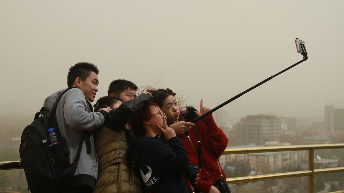 Tourists use a selfie stick during a heavy sandstorm in Beijing on Saturday, March 28.
