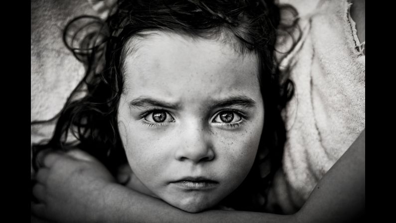 Ella, 9, holds her sister Alice, 6, after playing in the sprinkler. Alice's eyes are bloodshot from opening her eyes in the water, Parker said, and she wanted to keep it in the image. "It's a real person in there," she said.