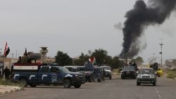 Smoke rises from buildings as Iraqi security forces patrol a street in Tikrit, on April 1, 2015, a day after the prime minister declared victory in the weeks-long battle to retake the city from the Islamic State (IS) group