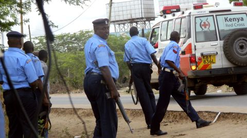 Police officers take positions outside the school as an ambulance carries victims to a hospital in Garissa.