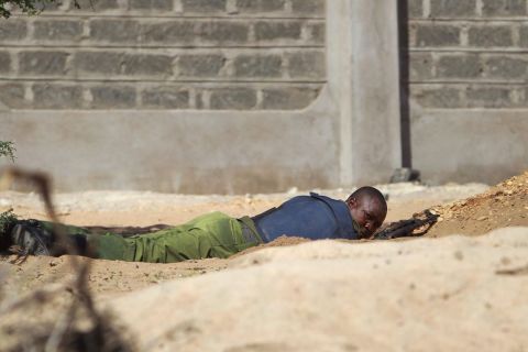 A Kenyan soldier takes cover as shots are fired in front of the school on April 2, 2015.