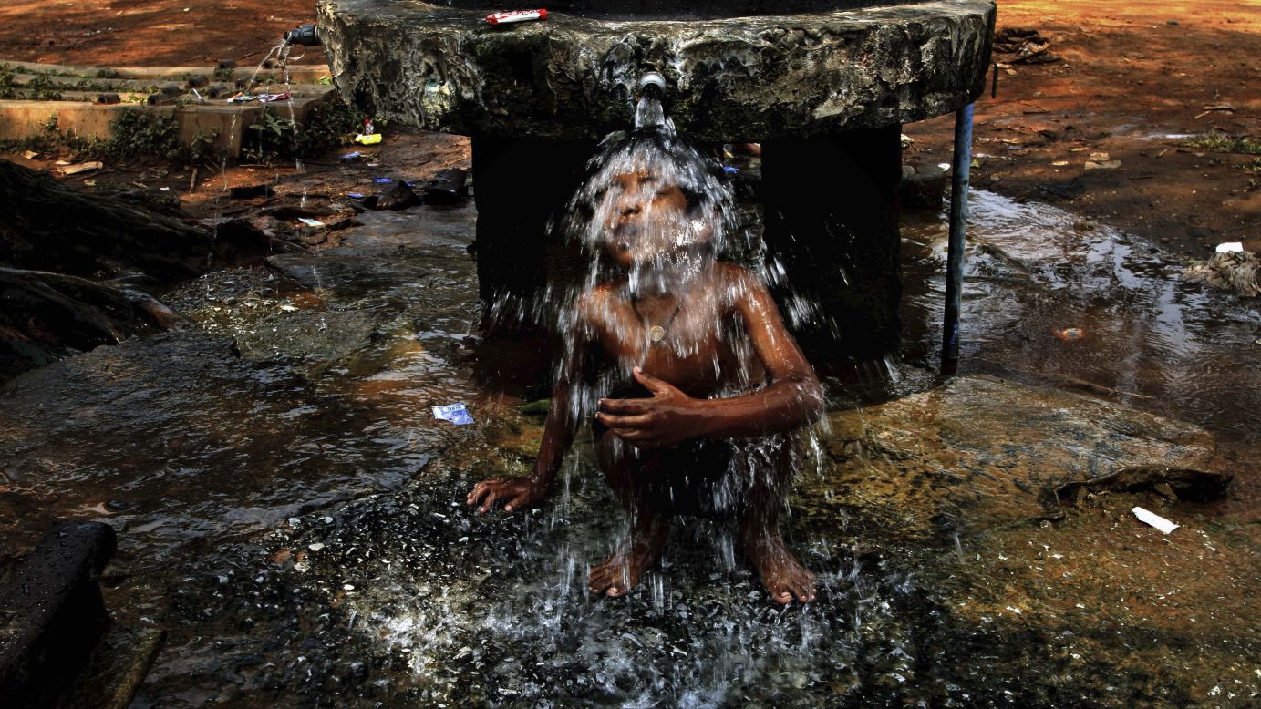 A boy sits under a roadside water tap during a hot day in Bhubaneswar, India, on Friday, March 27.