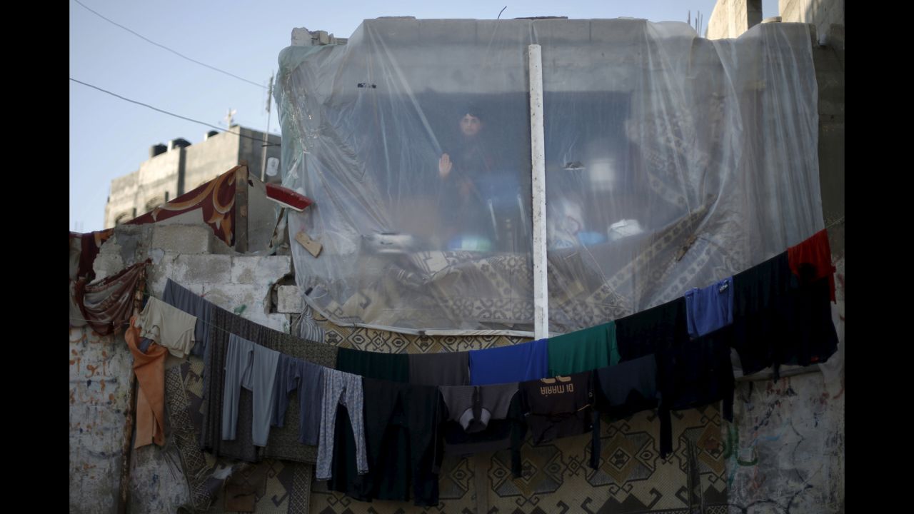 A Palestinian boy looks through a sheet covering the remains of his family's house in Beit Hanoun, Gaza, on Tuesday, March 31. Witnesses said the house was heavily damaged by Israeli shelling during its war with Hamas last summer.