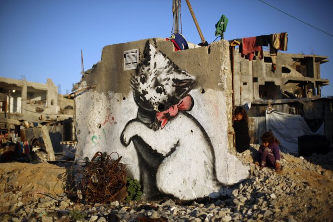 Un niño palestino se encuentra junto a un mural de Bansky de un gatito en medio de los restos de una casa destruida en Bait Hanun, Gaza, el jueves 26 de febrero. 