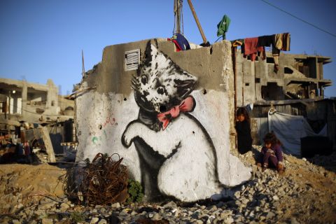 A Palestinian child stands next to a Banksy mural of a kitten on the remains of a destroyed house in Beit Hanoun, Gaza, in February 2015. 