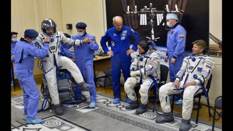 Kornienko tests his spacesuit as Kelly and Padalka wait their turn on March 27.