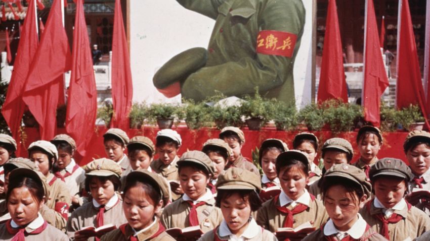 circa 1968: A group of Chinese children in uniform in front of a picture of Chairman Mao Zedong (1893 - 1976) holding Mao's 'Little Red Book' during China's Cultural Revolution.