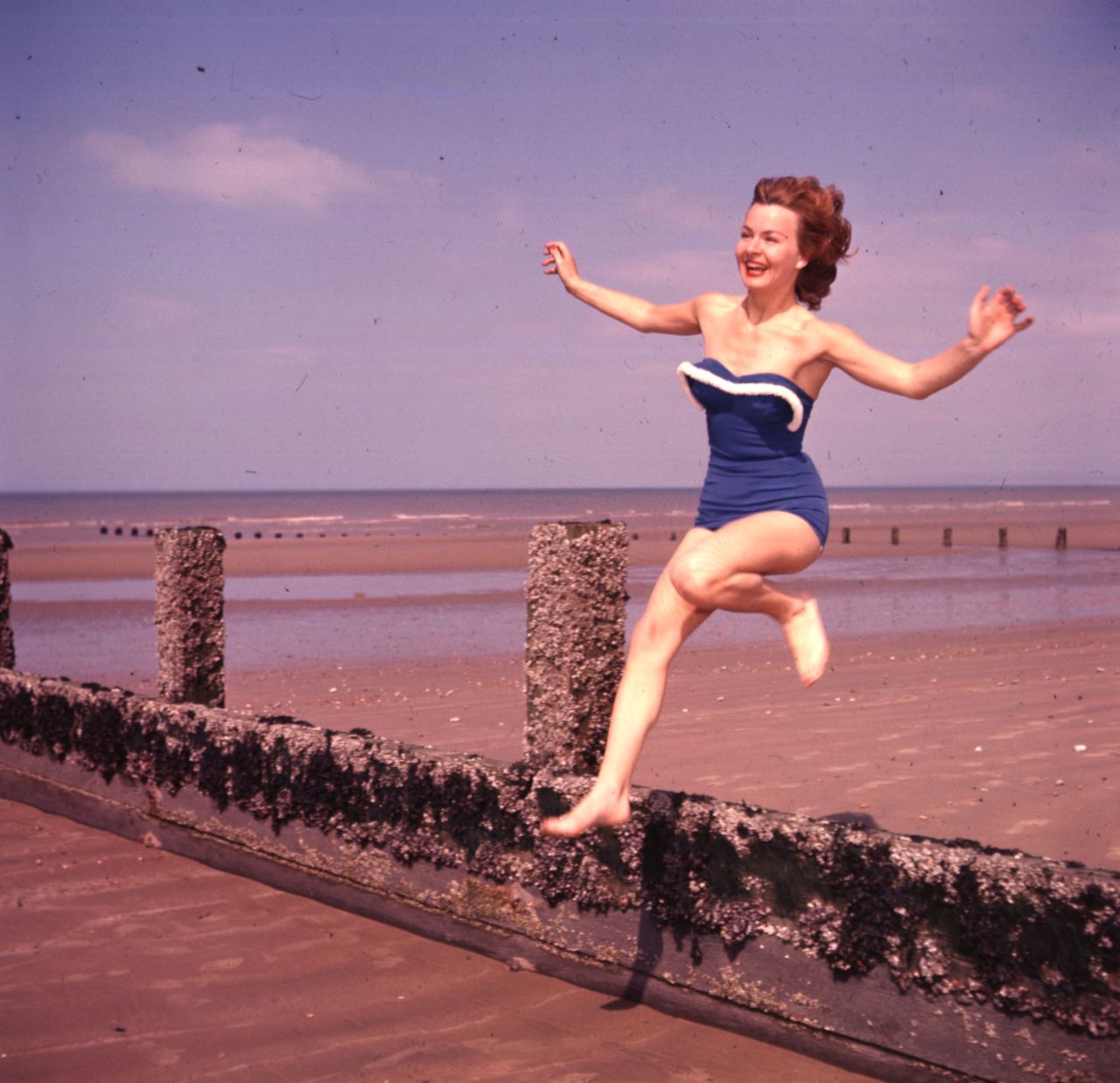 From sailor suits to pirate accessories, our love affair with nautical fashion has weathered many a storm. We take a look back at some of history's most enduring designs -- and their origins in mariner work wear. <br />Here, actress Marianne Brauns leaps over a breakwater on the beach, wearing a structured blue swimsuit with white trim, in 1950.