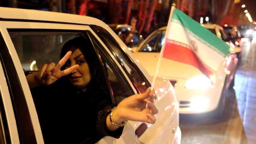 A woman in a car flashes the "V for Victory" sign and waves an Iranian flag as people celebrate on Valiasr street in northern Tehran on April 2, 2015, after the announcement of an agreement on Iran nuclear talks. Iran and global powers sealed a deal on April 2 on plans to curb Tehran's chances for getting a nuclear bomb, laying the ground for a new relationship between the Islamic republic and the West. AFP PHOTO / ATTA KENAREATTA KENARE/AFP/Getty Images