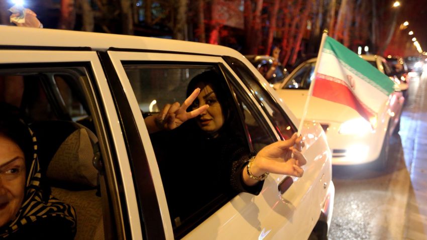 A woman in a car flashes the 'V for Victory' sign and waves an Iranian flag as people celebrate on Valiasr street in northern Tehran on April 2, 2015, after the announcement of an agreement on Iran nuclear talks. Iran and global powers sealed a deal on April 2 on plans to curb Tehran's chances for getting a nuclear bomb, laying the ground for a new relationship between the Islamic republic and the West. AFP PHOTO / ATTA KENARE (Photo credit should read ATTA KENARE/AFP/Getty Images)
