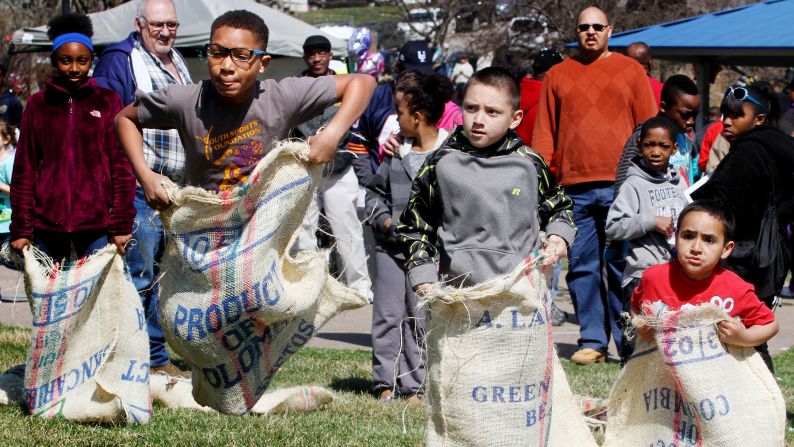 Roman Taliafero, second from left, leads the sack race against Danny McCleary and Cayten McCleary, right, during an April 4 Easter egg hunt  sponsored by People Uniting Neighbors and Churches, at Cork Hill Park in Davenport, Iowa.