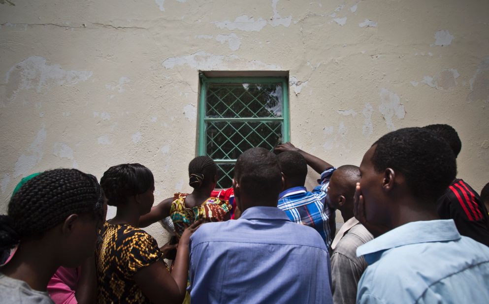People in Garissa crowd around a mortuary window on April 4, 2015, to view the bodies of the alleged attackers. Authorities later paraded the bodies through a crowd on the bed of a pickup truck. 