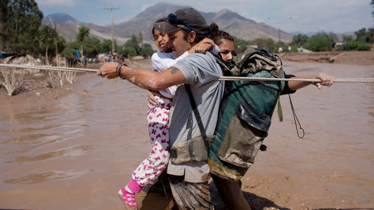 A family holds onto a rope as they cross a flooded street in Copiapo on March 26.