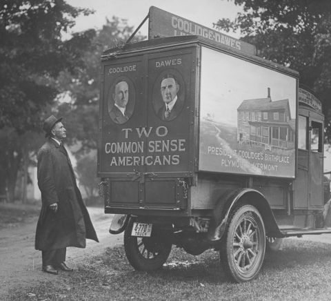 Calvin Coolidge inspects a campaign truck painted with images of Coolidge and his running mate, Coolidge's birthplace in Plymouth, Vermont, and the campaign slogan, "Two common sense Americans," circa 1929.
