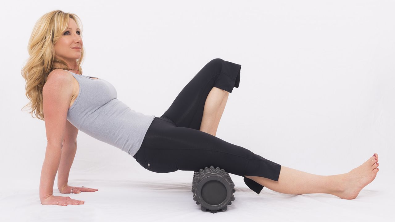 Rest your hamstrings (back of upper legs) on the roller with both hands on the floor behind you for support. Bend one knee to place a foot on the roller. Roll your hamstrings from the fold of your glute (bottom) to just above the back of your knees. Repeat on the other side.