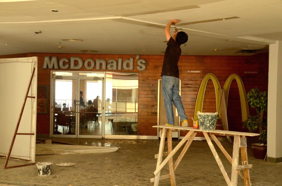 A construction worker fixes a ceiling outside a McDonald's restaurant,  New South China Mall. <br />
