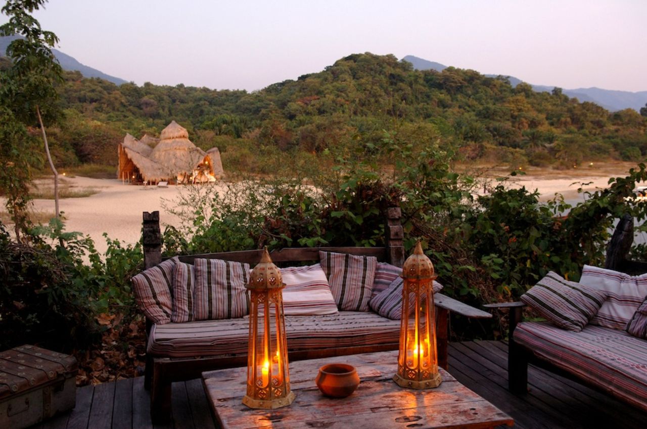 "The Greystoke lodge perches on a beach sandwiched between the waters of Lake Tanganyika and the forested, emerald green Mahale Mountains. This is the number one place in Africa to see chimpanzees. The lodge consists of palm-frond thatching and timbers taken from disused boats on the lake."