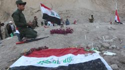An Iraqi Shiite fighter and member of Iraq's Popular Mobilisation, prays at a burial site believed to hold victims of a June massacre in which hundreds of army cadets were executed by the Islamic State (IS) group, in the city of Tikrit, on April 4, 2015