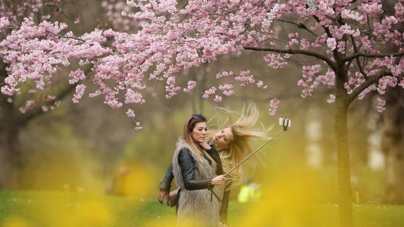 Two women take a selfie under blossom trees in London on Wednesday, April 1.